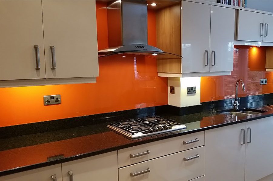 Kitchen with bright orange painted glass splashbacks