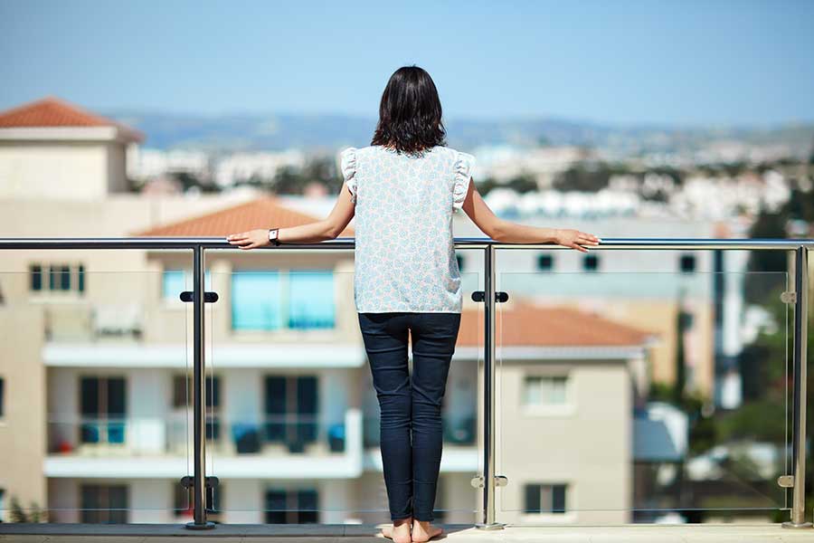 Woman looking at a city view from a glass balcony
