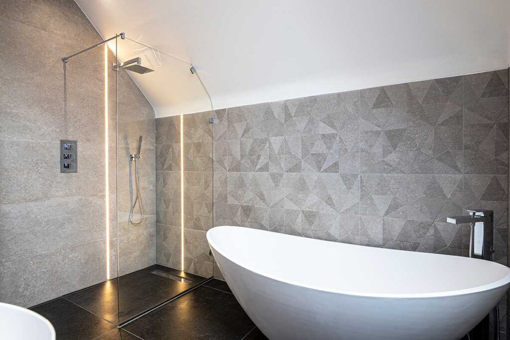 Angled frameless shower screen glass installed in a luxurious loft conversion bathroom in Dorset by Room H2o