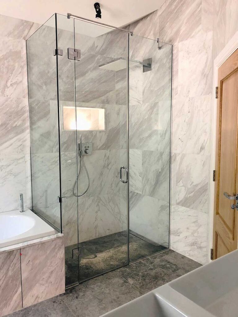 Large end of bath frameless glass wet room shower enclosure with hinged door