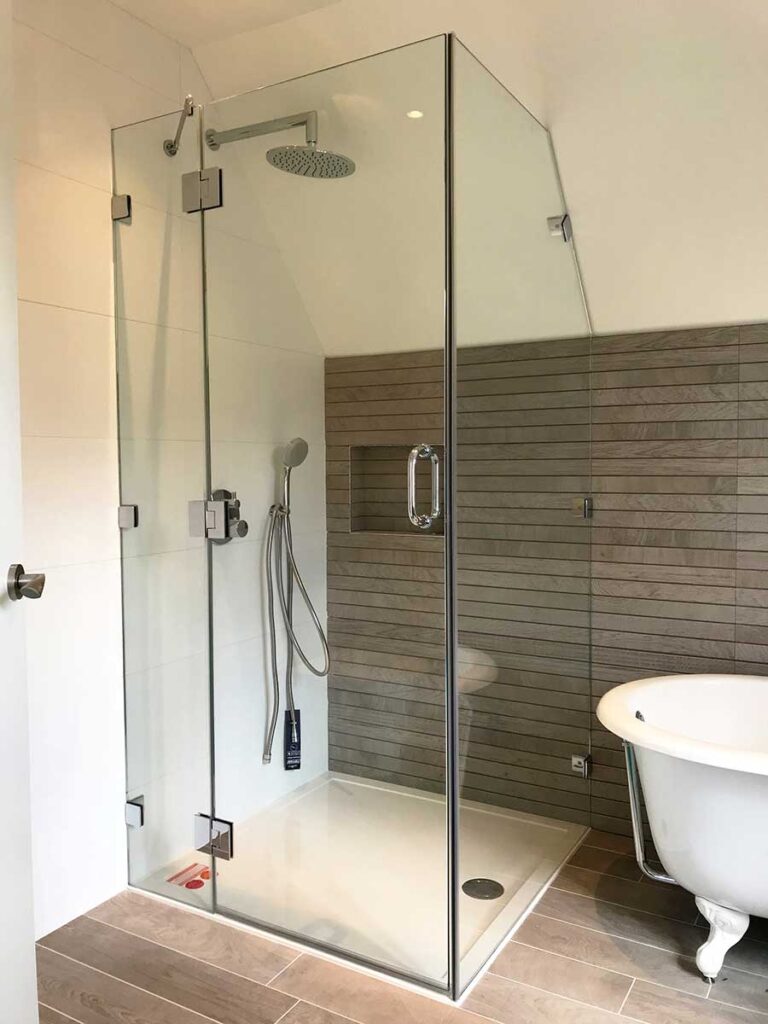 Frameless shower enclosure with angled side panel shaped to fit the ceiling in a loft conversion